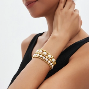 Meerlaagse 14K gouden kralen en witte parel armbandset gedragen door vrouwelijk model