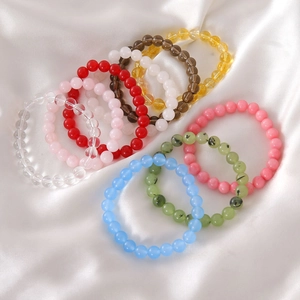 Detail of colorful 8mm glass and stone bead bracelets on white silk background