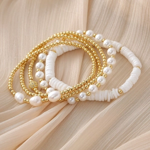 Baroque pearl and gold beaded stretch bracelet set on neutral textured fabric