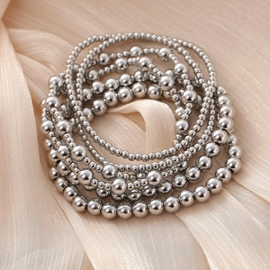 Bohemian multilayer stackable metal bead bracelets on champagne silk fabric background