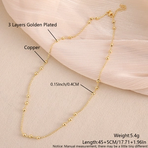 Detail van de 3-laags vergulde koperen ketting met platte kralen op geplooide stof