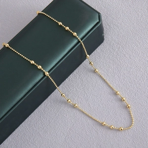 Elegante gouden kralenketting op een donkergroen juwelendoosje op paarse zijden achtergrond