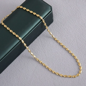 Gepolijste gouden koffieboon ketting gepresenteerd op een juwelendoos en paarse achtergrond