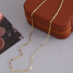 Elegante collana a catena a graffetta dorata su una superficie grigia materica