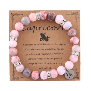 Pink zebra jasper Capricorn zodiac stretch bracelet with silver charms on display card