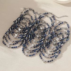 Bracelet de perles bleues avec breloque cœur alphabet en acier sur surface sable