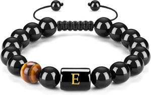 Detalle de la pulsera de cuentas negras con ojo de tigre y dije dorado de la letra E