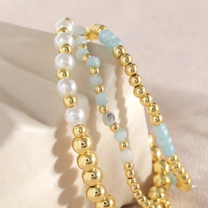 Stackable three-piece bead bracelet set with white pearls, blue stones and gold beads