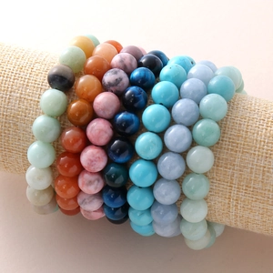 Pulseras de piedras naturales ojo de tigre y ágata en un soporte de joyería de lino