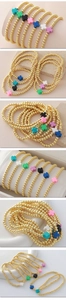 Detalle macro de pulseras elásticas con cuentas doradas y cruces mates de colores