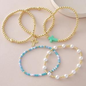 Détail de l'ensemble de 5 bracelets perlés dorés avec pendentif croix et perles d'imitation