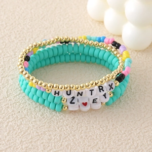 Pulsera multicapa hecha a mano con cuentas doradas, dijes de colores y letras