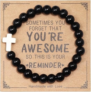Detail of handmade black beaded bracelet with white cross charm on gift card