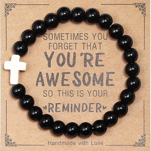 Handmade black volcanic stone beaded bracelet with a white cross on an inspirational card
