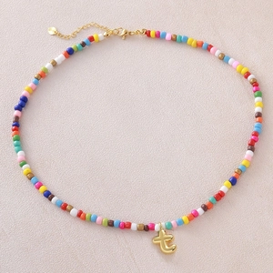 Dettaglio di collana con perline colorate, chiusura dorata e pendente a cuore