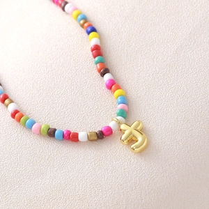 Macro di una collana di perline colorate con pendente a lettera bubble placcato oro