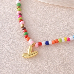 Dettaglio macro di una collana di perline multicolore con pendente a V placcato in oro