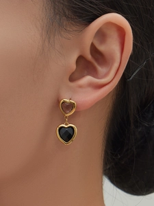 Detailaufnahme von doppelt herzförmigen Ohrringen in Gold am Ohr eines Models