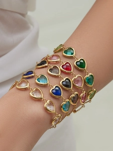 Detailansicht von facettierten Herz-Edelsteinen an vergoldeten Armbändern in bunten Farben