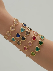 Nahaufnahme von bunten herzförmigen Glassteinen auf 18k vergoldeten Armbändern