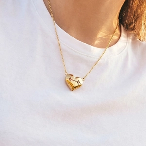 Collana a cuore in oro minimalista con design battito cardiaco su t-shirt bianca