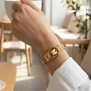 Women's gold mesh strap bracelet with horseshoe buckle on wrist with white shirt