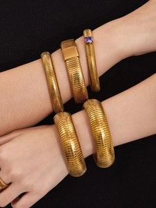 Détail de bracelets élastiques dorés en maille serpent avec zircon violet et boucle carrée