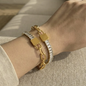 Gouden hangslot ketting armband set met vierkante zirkoon op een stoffen achtergrond