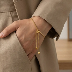 Adjustable gold snake bone chain bracelet worn with a khaki suit jacket for women