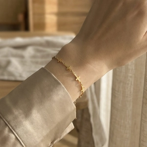 Golden multi-cross chain bracelet with minimalist geometric design worn on a female wrist