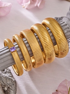 Détail de cinq bracelets Tubogas extensibles plaqués or 18k avec une pierre violette carrée
