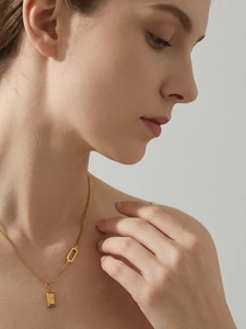 Detail of 18k gold plated bar necklace with LOVE engraving worn by a female model