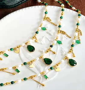 Dettaglio della collana boho con perle di malachite verde e ciondoli a cuore dorati