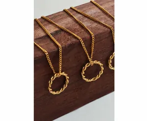 Detailed macro view of gold-plated twisted rope circle pendant on multiple long chains