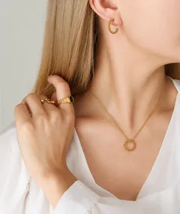 Detail of twisted gold jewelry set with green gemstone ring on elegant female model