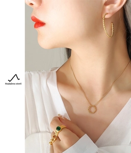 Detail of model wearing golden twisted cable hoop earrings and matching circle necklace