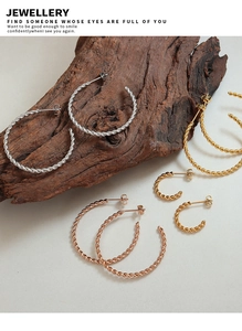Macro detail of twisted C-shaped hoop earrings in gold, silver, and rose gold finishes