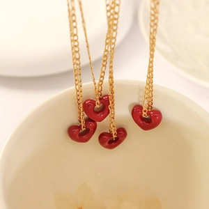 Elegantes Goldketten-Set mit hohlen roten Herzanhängern an einer weißen Keramiktasse