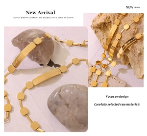 Close-up of golden snake chain bracelet with engraved rectangular plate on stone base