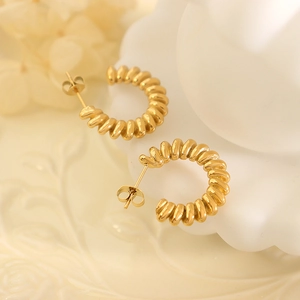 Retro golden C-shape earrings with vintage spiral texture on white ceramic base