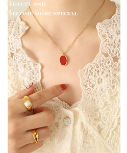 Close-up of a gold necklace with red oval pendant and pearl ring on lace fabric