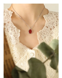 Vintage French style silver necklace with an oval red pendant on a model's neck