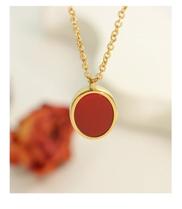 Macro detail of oval red pendant with gold-plated metal frame on a fine chain