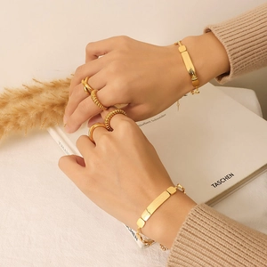 Elegant gold titanium steel bracelet and stacked textured rings set on a model hand