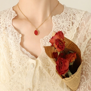 Elegant gold necklace with a red oval pendant displayed on a model in vintage style