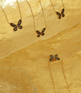Détail de pendentifs papillon plaqués or 18 carats avec émail noir et chaîne dorée