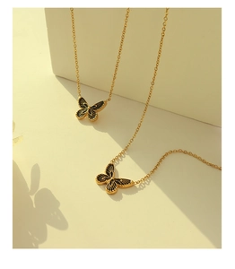 Détail de deux pendentifs papillon noirs sur chaînes dorées avec des ombres