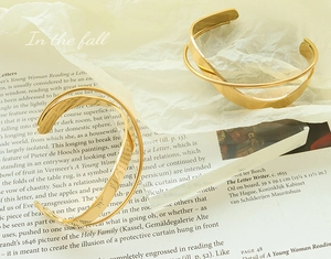 Detailed view of gold cross open bangle with dual layer minimalist stainless steel design