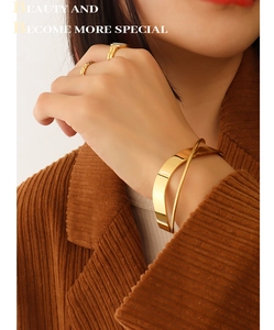 Close-up of polished gold-finished crisscross cuff bracelet worn by a model