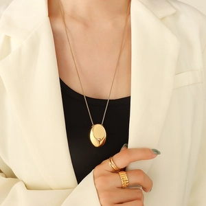 Collier vintage français avec pendentif ovale et bagues dorées portés par un modèle